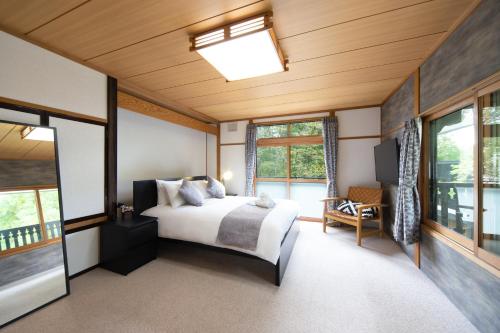 - une chambre avec un lit dans une pièce dotée de fenêtres dans l'établissement THE CASTLE by Hakuba Hotel Group, à Hakuba