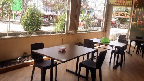 two tables and chairs in a restaurant with windows at Gold Line Guest House in Pontianak