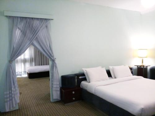 a hotel room with two beds and a window at Oriental Palace Hotel in Manama