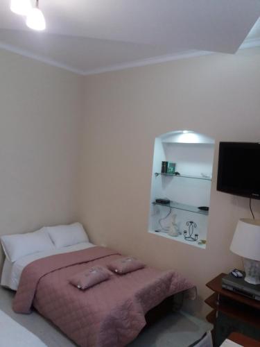 a bedroom with a bed with pink sheets and a tv at Центрові апартаменти in Ivano-Frankivsʼk