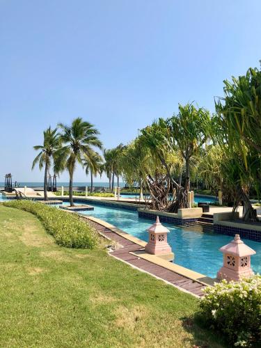 a swimming pool with palm trees and the ocean at Boathouse Hua Hin Seaview in Ban Bo Fai