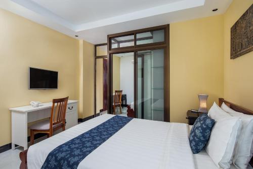 a bedroom with a bed and a desk and a television at Botum Palace Hotel in Phnom Penh