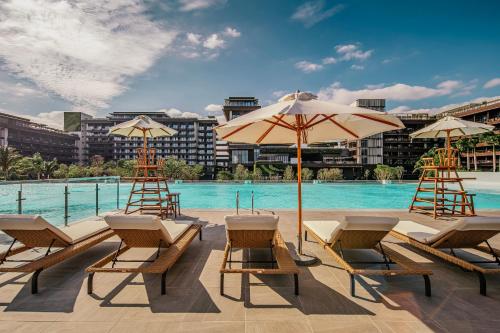 a group of chairs and umbrellas next to a pool at 1 Hotel Haitang Bay, Sanya in Sanya