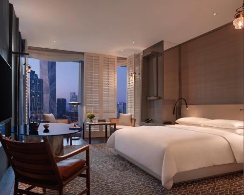 Un dormitorio con cama y escritorio y una habitación con vistas. en Andaz Shenzhen Bay, en Shenzhen