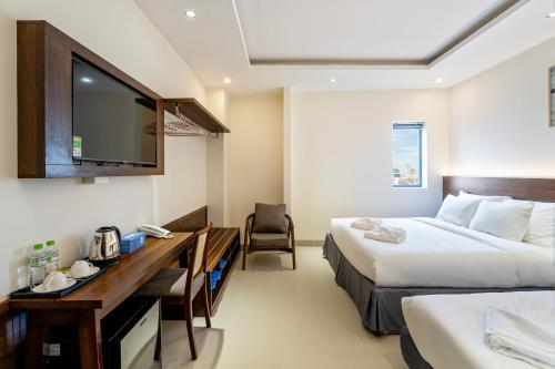 a hotel room with two beds and a desk and a tv at Aquatel Vung Tau in Vung Tau