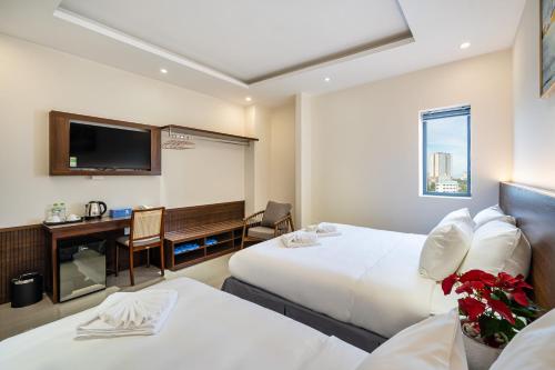 a hotel room with two beds and a desk at Aquatel Vung Tau in Vung Tau