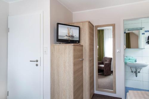 un bagno con TV in cima a un armadio di Pension Ursula a Neuharlingersiel