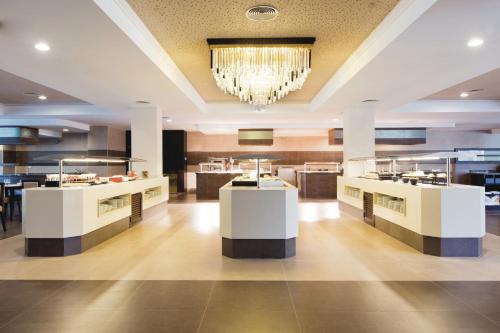 a restaurant with white counters and a chandelier at Hotel Riu Bravo - 0'0 All Inclusive in Playa de Palma