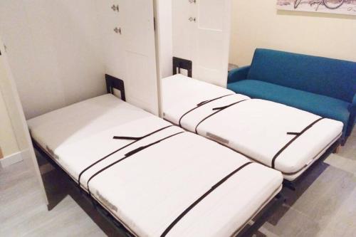 a room with three beds and a blue couch at R22-Loft en Madrid con aire acondicionado y Wifi in Madrid