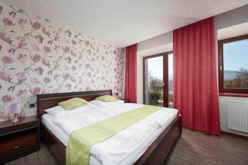 a bedroom with a large bed with a floral wall at Hotel Slunný Dvůr in Jeseník