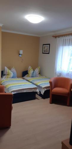 two beds in a room with a couch and a chair at Antal Apartmanok in Zalakaros