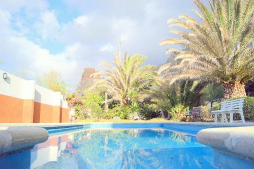 una piscina con palmeras y una silla blanca en La Quinta del Tarajal, en Garafía