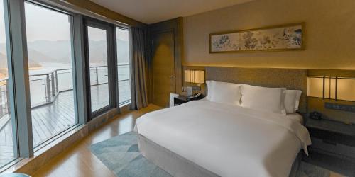 a bedroom with a large white bed and large windows at Crowne Plaza Hangzhou Thousand Island Lake by IHG in Thousand Island Lake