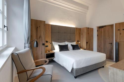 a bedroom with a white bed and a chair at Castel Hörtenberg in Bolzano