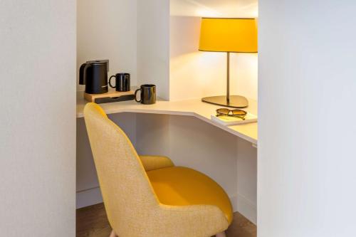 a desk with a yellow chair and a lamp at Best Western Hotel du Roy d'Aragon in Bonifacio
