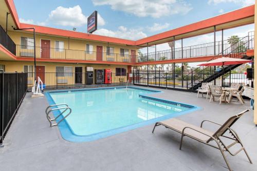 a pool at a hotel with two chairs and a table at Howard Johnson Suites by Wyndham San Diego Chula Vista BayFt in Chula Vista