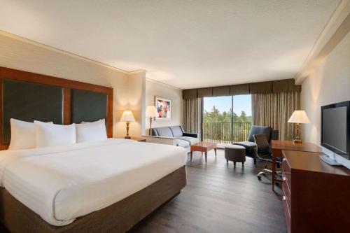 a hotel room with a large bed and a television at Baymont by Wyndham Bremerton WA in Bremerton