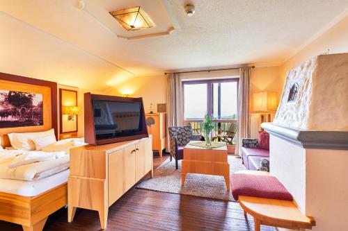 a living room with a television and a couch at Wellnesshotel Riedlberg in Drachselsried