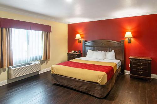 a hotel room with a large bed with red walls at Econo Lodge Long Beach I-405 in Long Beach