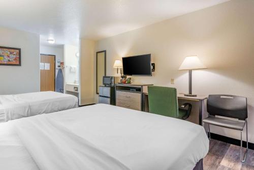 a hotel room with two beds and a desk and a tv at Econo Lodge Pueblo North in Pueblo