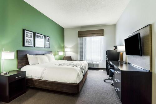 a hotel room with a bed and a desk and a television at Sleep Inn & Suites Smithfield near I-95 in Smithfield