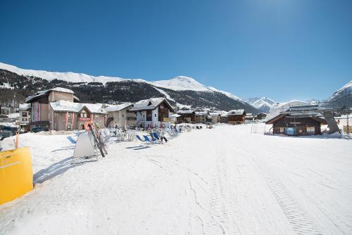 a snow covered road with houses and mountains in the background at Hotel Centro's in Livigno