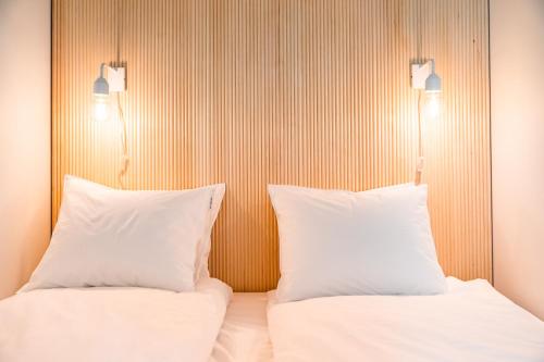 two beds with white pillows sitting next to each other at Apartment City in Oulu