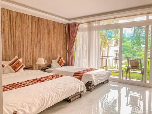 a hotel room with two beds and a balcony at Mai Chau Sunset Boutique Hotel in Mai Chau