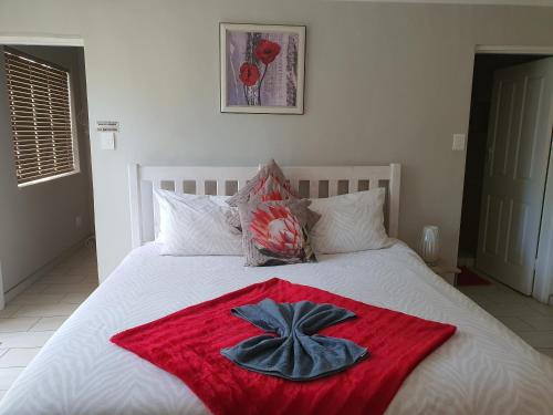 a bed with a red blanket and a hat on it at Chic Breeze in Bloemfontein