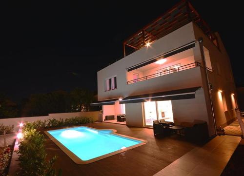 een zwembad voor een huis 's nachts bij Apartment 2 with the swimming pool in Turanj