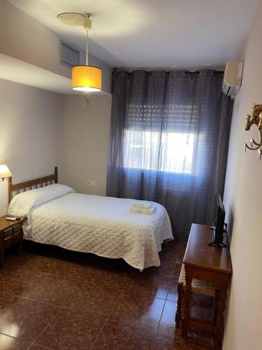 a bedroom with a bed and a window at Hostal Parapanda in Granada