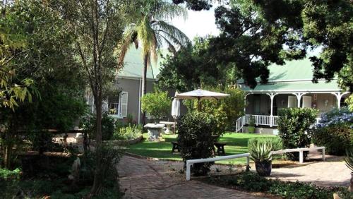 a house with a garden with a table and an umbrella at HouseMartin Lodge & Self Catering in De Rust