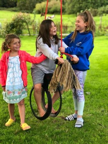 three girls playing on a swing in the grass at South Barlogan Farm in Bridge of Weir