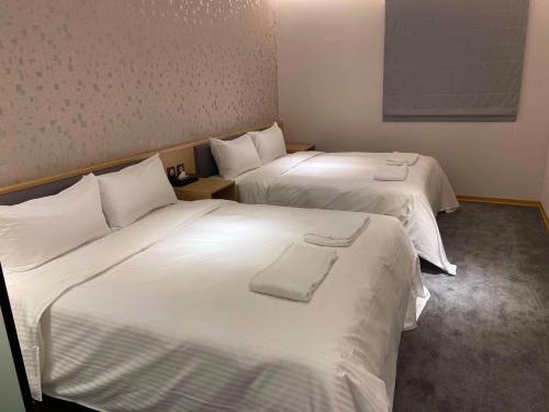 two beds in a hotel room with white sheets at Michi Hotel - Zhongli in Zhongli