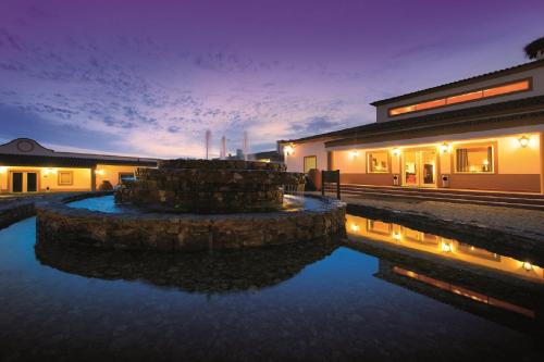 a house with a pond in front of a building at Vila Gale Alentejo Vineyard - Clube de Campo in Albernoa