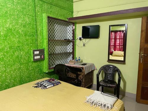a green room with a bed and a table and a mirror at Nimmu Guest House & Restaurant Gokarna in Gokarna