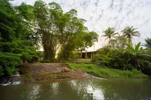 a house next to a river with trees at Pousada Toca da Coruja in Bonito