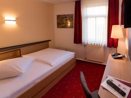 a hotel room with a bed and a chair at Hotel Pension Treppengasse Nr. 5 in Altenburg