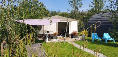 a pink umbrella and two blue chairs in a yard at The Little Hide - Grown Up Glamping in Wigginton