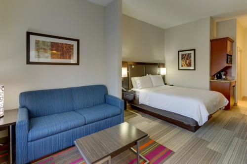 a hotel room with a bed and a blue couch at Holiday Inn Express Hotel & Suites Dayton-Centerville by IHG in Centerville