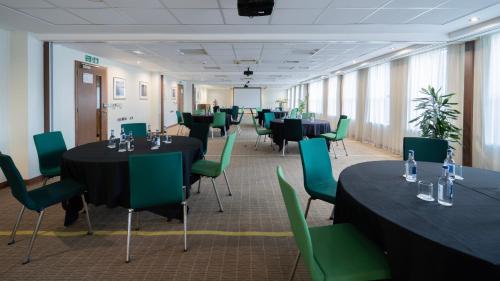 a conference room with tables and green chairs at Holiday Inn Bristol City Centre by IHG in Bristol