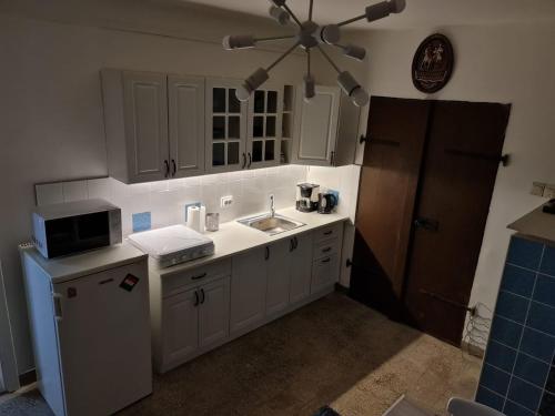 a kitchen with white cabinets and a sink at Het Hongaarse Wijnhuis in Mohács