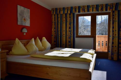 a bedroom with a bed with red walls and a window at Haus Garber in Zell am Ziller