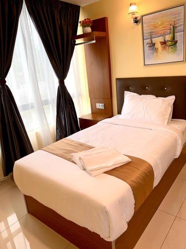 a large bed in a room with a large window at Hotel Selesa in Sungai Buluh