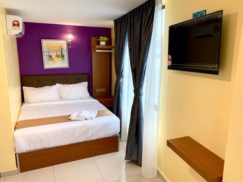 um quarto com uma cama e uma televisão de ecrã plano em Hotel Selesa em Sungai Buluh