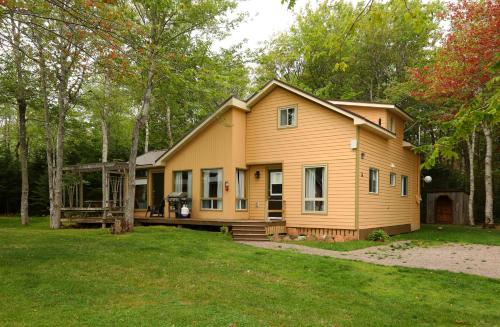 a small yellow house in the middle of a yard at Cavendish Maples Cottages in Cavendish