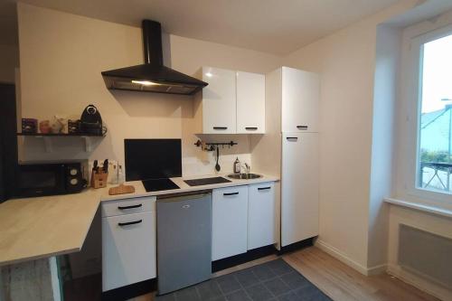 cocina con armarios blancos y encimera en Appartement T2 cosy et chaleureux - 40mn de Rennes, en Plumaugat