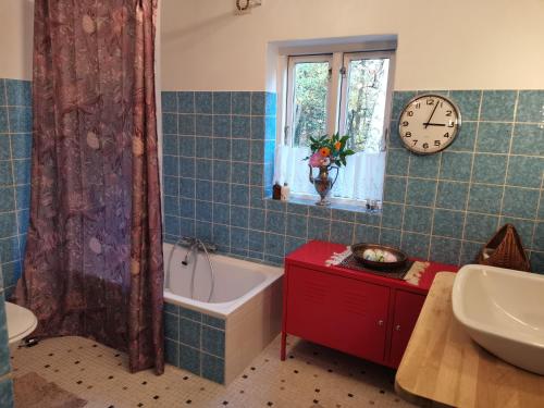 SvebølleMikrogaarden shared kitchen&bathroom的一间带浴缸的浴室和墙上的时钟