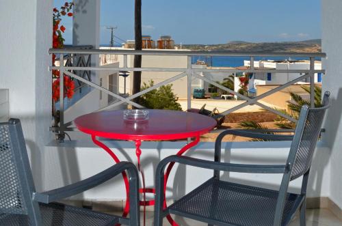 uma mesa vermelha e duas cadeiras numa varanda em Villa Ostria em Koufonisia