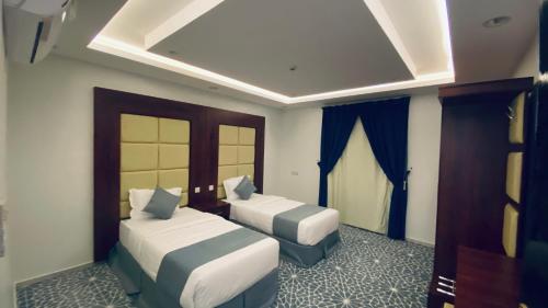 a hotel room with two beds and blue curtains at شقق بيات العالية وادي بن هشبل Bayat Al aliah Apartments in Wadi bin Hashbal in Bin Hashbal